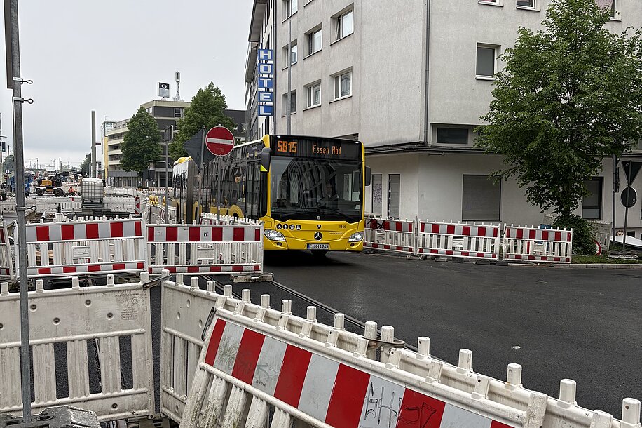 Ein Bus fährt auf einer Straße, an den Seiten sind links und rechts Baustellenabgrenzungen zu sehen