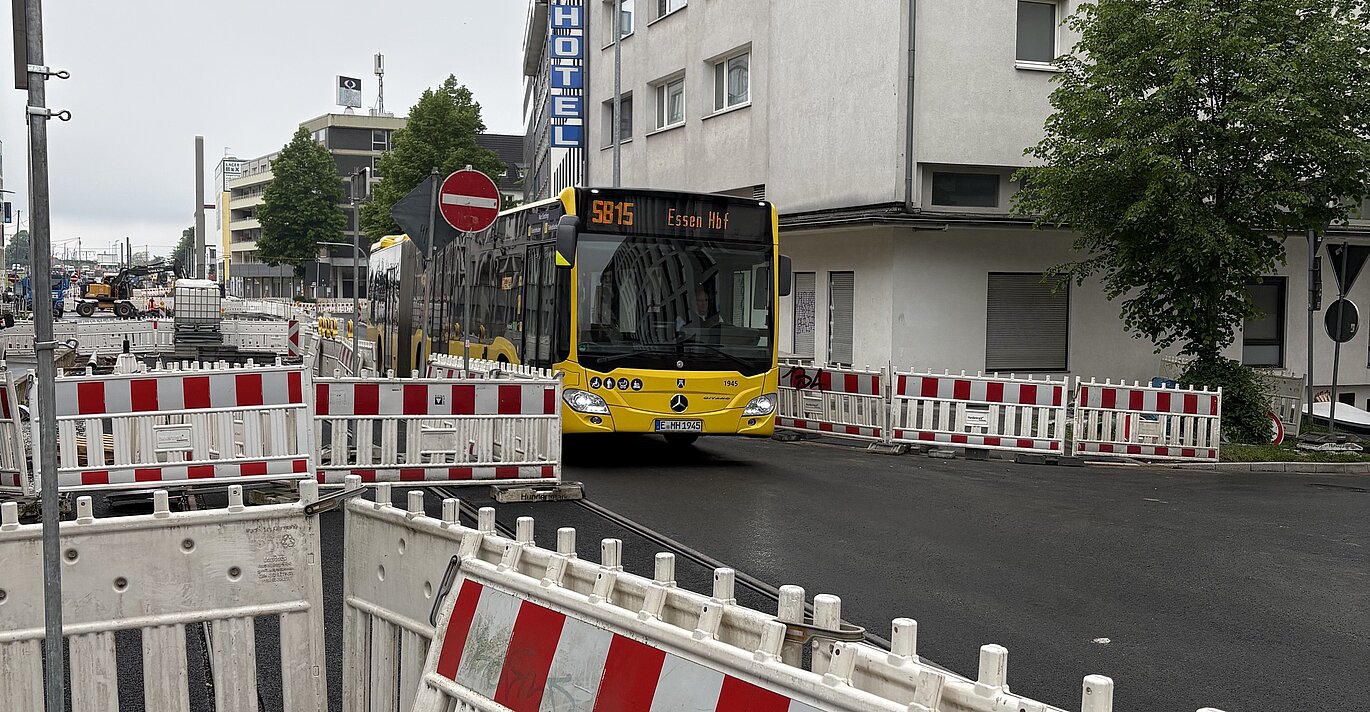 Ein Bus fährt auf einer Straße, an den Seiten sind links und rechts Baustellenabgrenzungen zu sehen