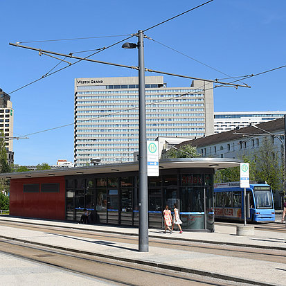 Beispielbild eines kegelfärmigen Mastes, der an einer Haltestelle für Busse und Straßenbahnen steht.